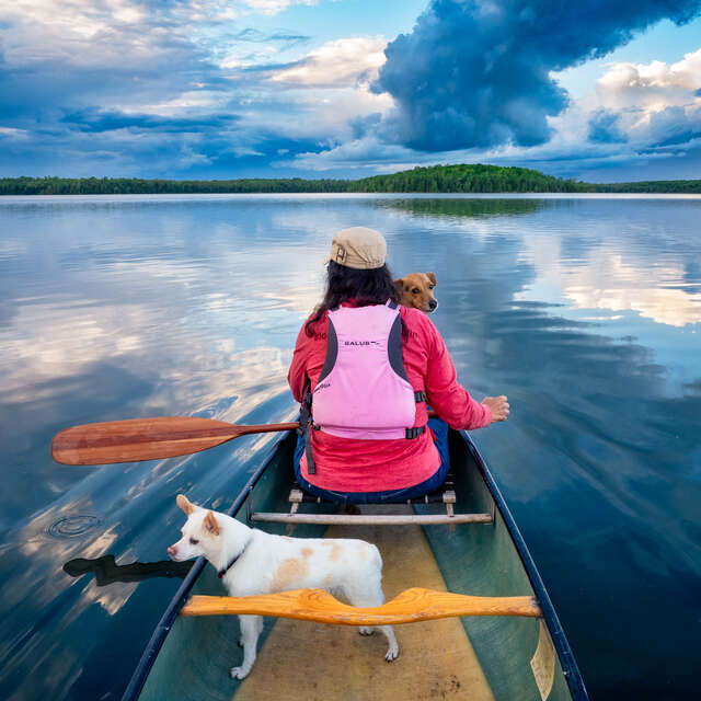 Woman and Dogs in Canoe on Lake