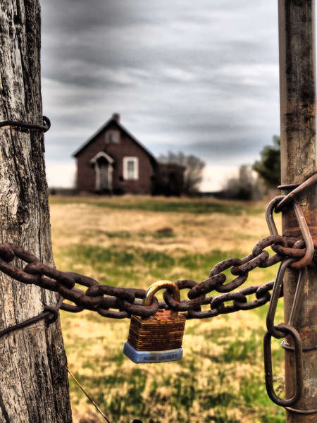Lock and chain with barn in background with dramatic sky